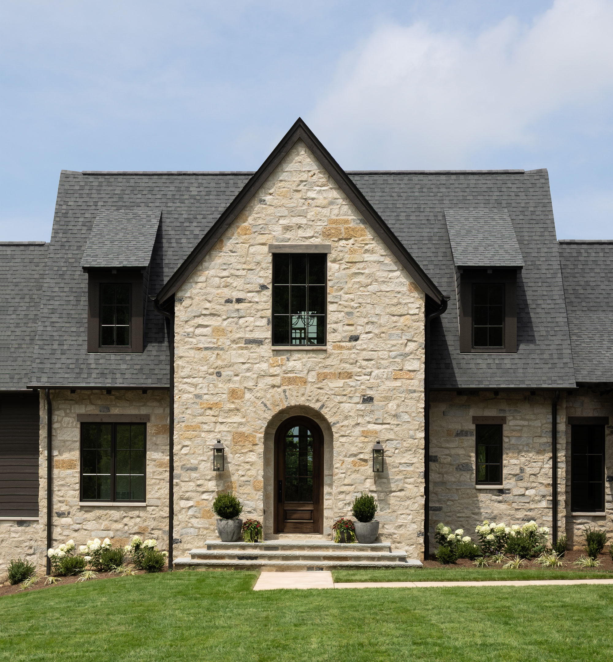 Front of the Summit house with overgrouted thin natural stone, limestone window sills and an arched front entry