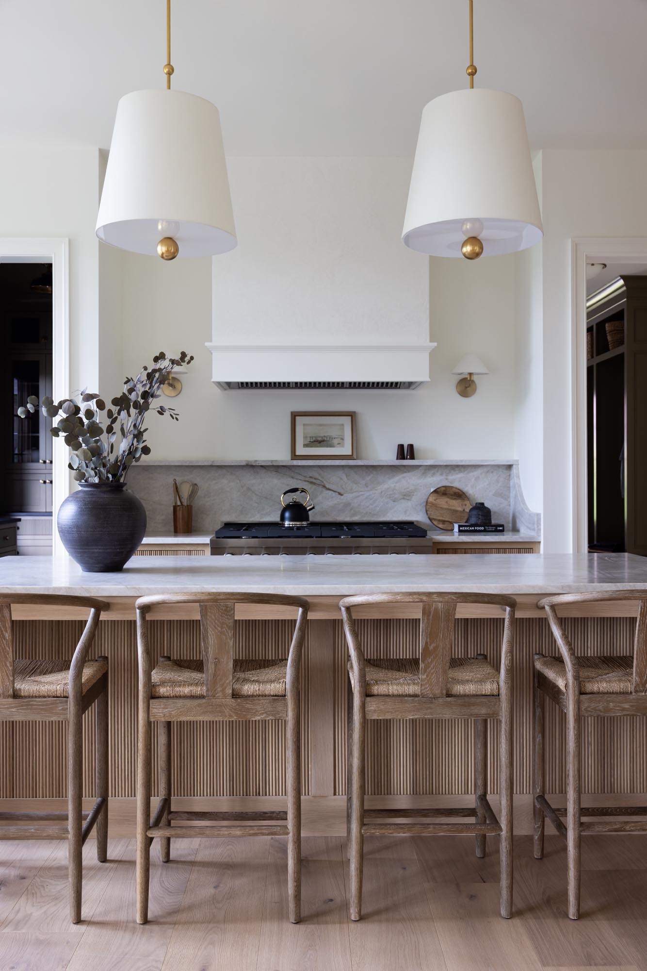 White oak kitchen island with reeded front, Taj Mahal quartzite countertop, oak counter stools and two McGee and Co Kipling pendants in the Summit kitchen