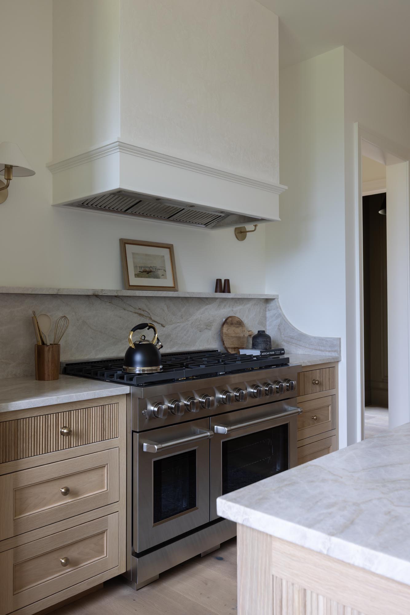 ZLINE 48 inch Paramount SDR48 range under a Hoodsly plaster hood with Taj Mahal quartzite backsplash and white oak cabinets