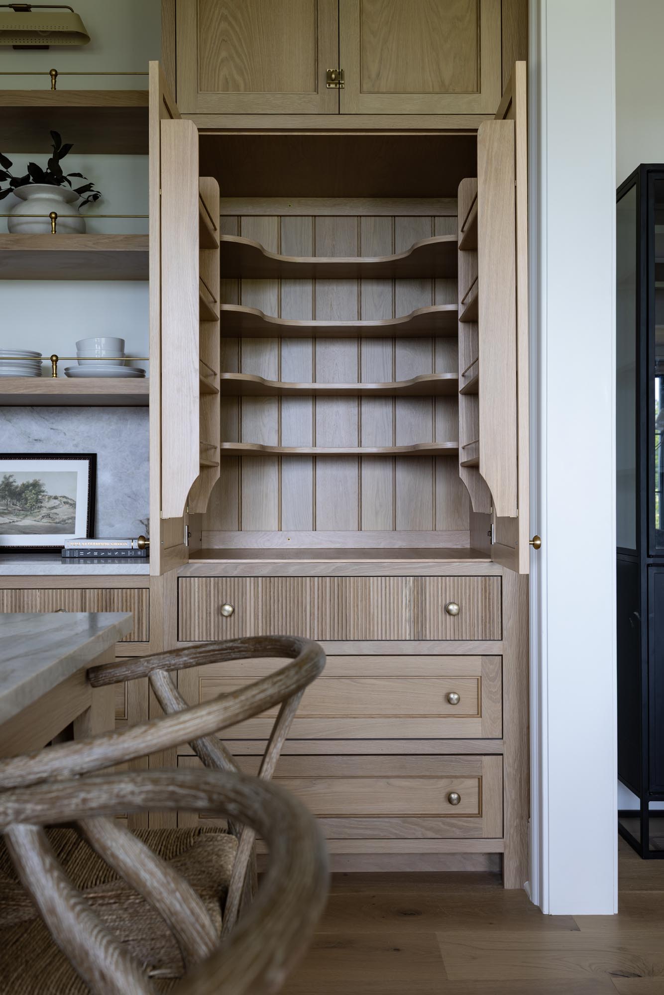 Open white oak pantry cabinet with scalloped shelves, door-mounted shelves and V-groove back
