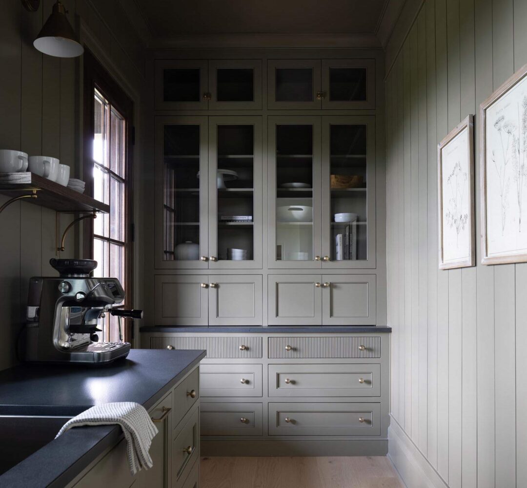 Finished scullery with Crownsville Gray cabinetry, dark counters, a wood shelf, and framed botanical prints.